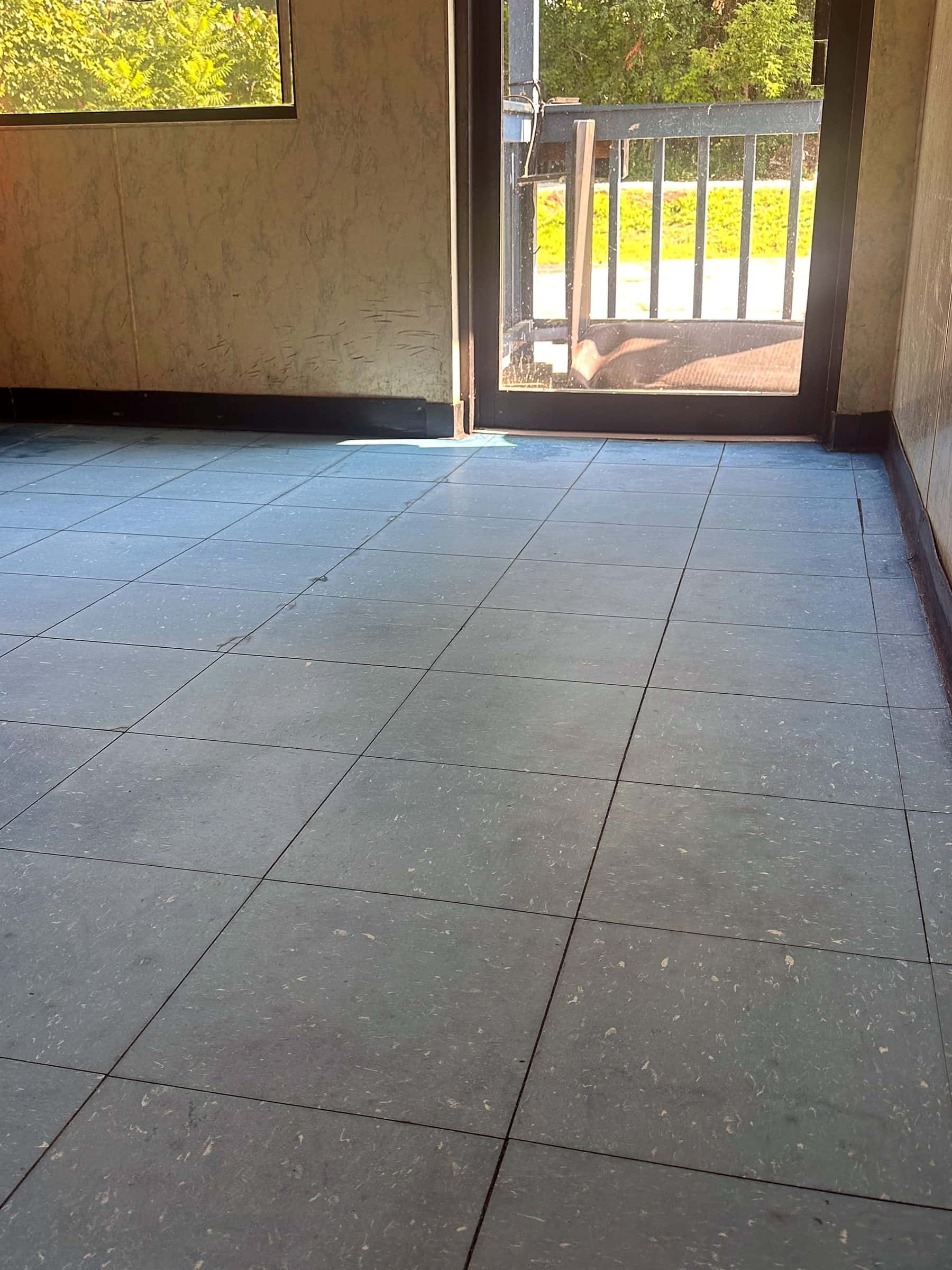 The same entrance floor before strip and wax, the tile dull and gray under the old finish.