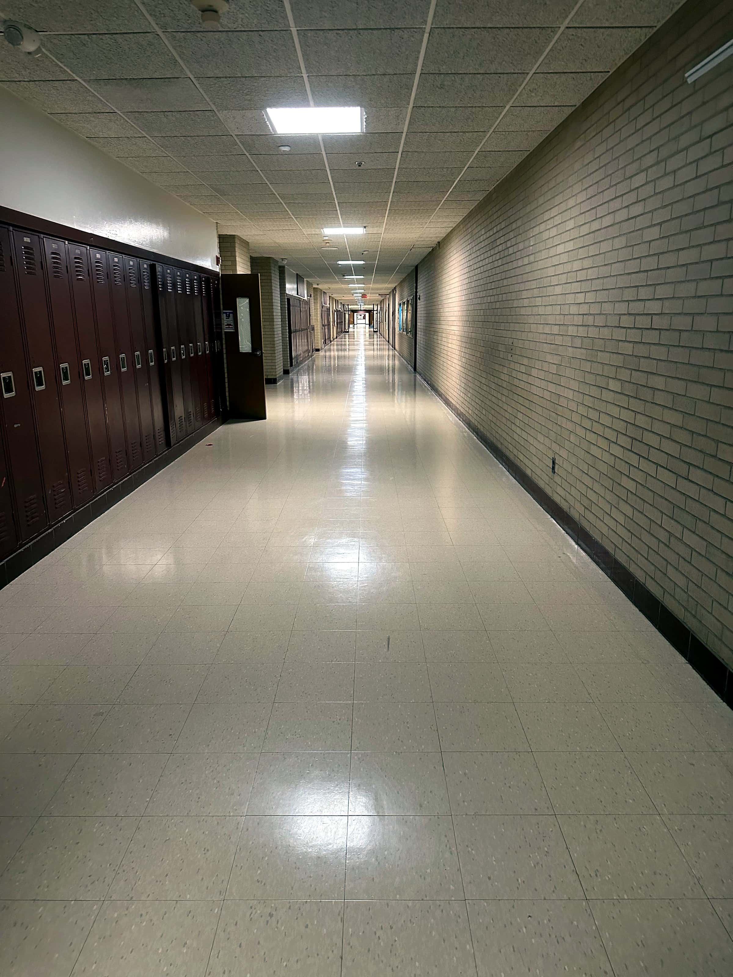 A school corridor with lockers and a freshly polished tile floor.