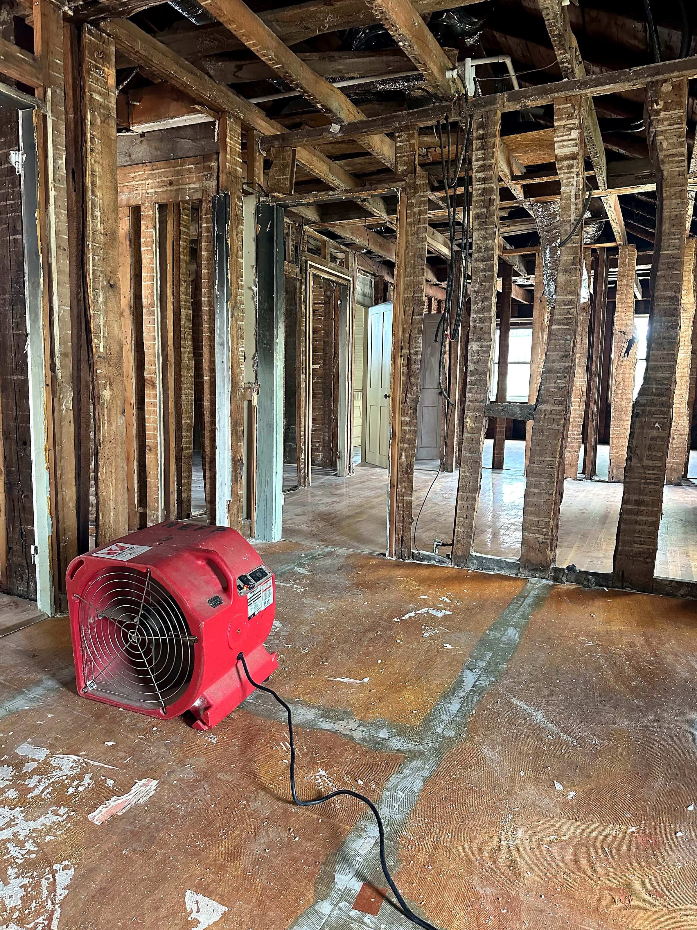 An air mover drying a room stripped to the studs after a water loss.